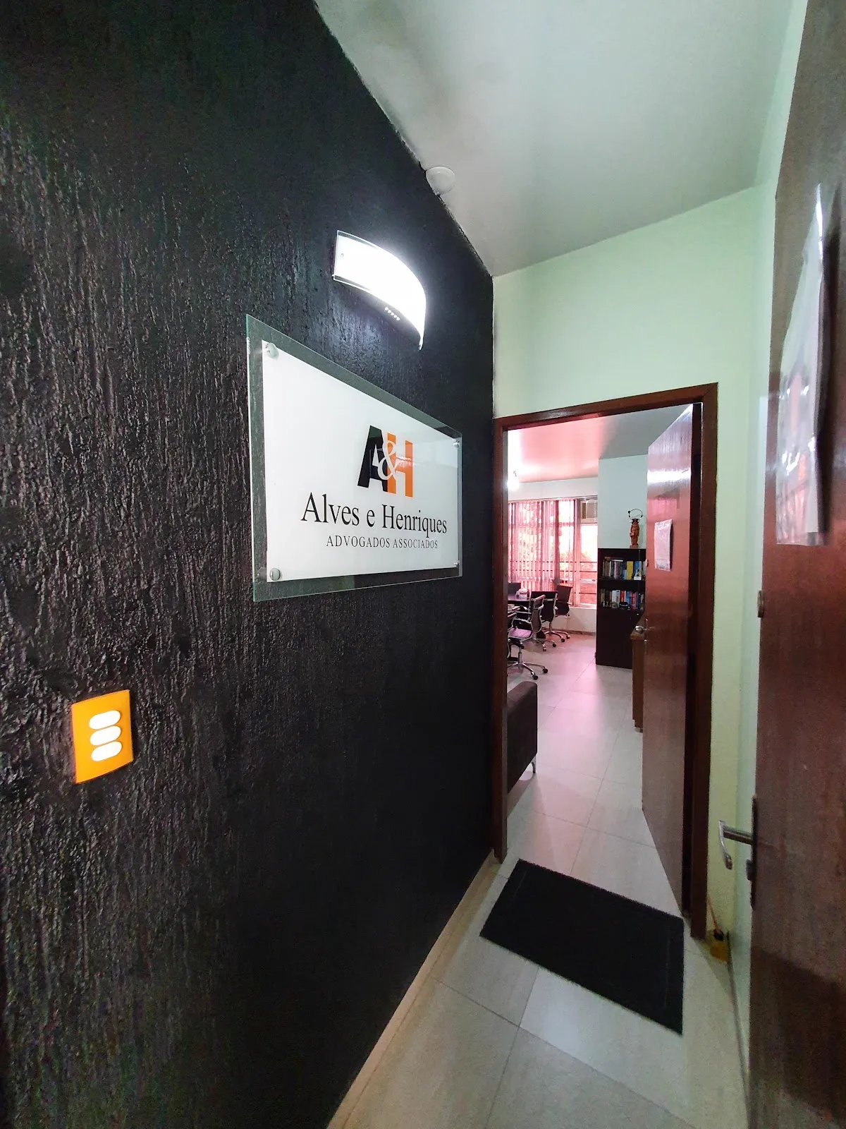 Placa de vidro com o logotipo A&H na parede da recepção